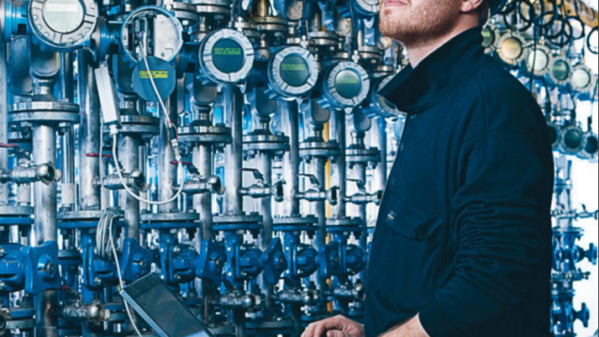 Init engineer with a laptop in front of rows of industrial flow meters
