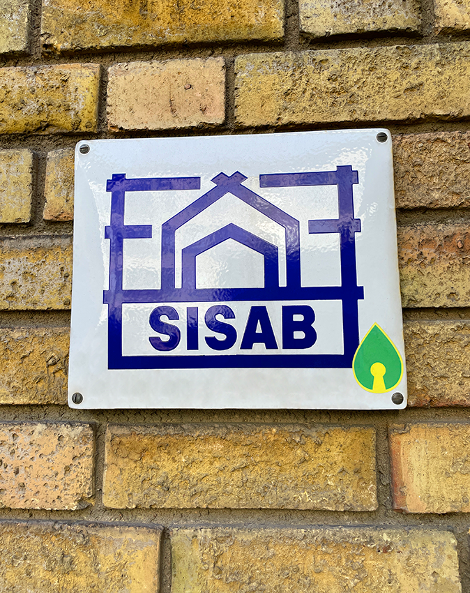Enamel sign with SISAB logo on yellow brick wall